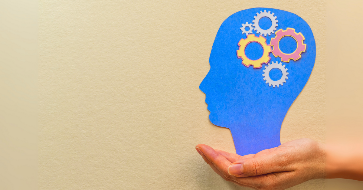 Hand holding blue silhouette of head with orange gears, representing guest psychology and decision-making processes