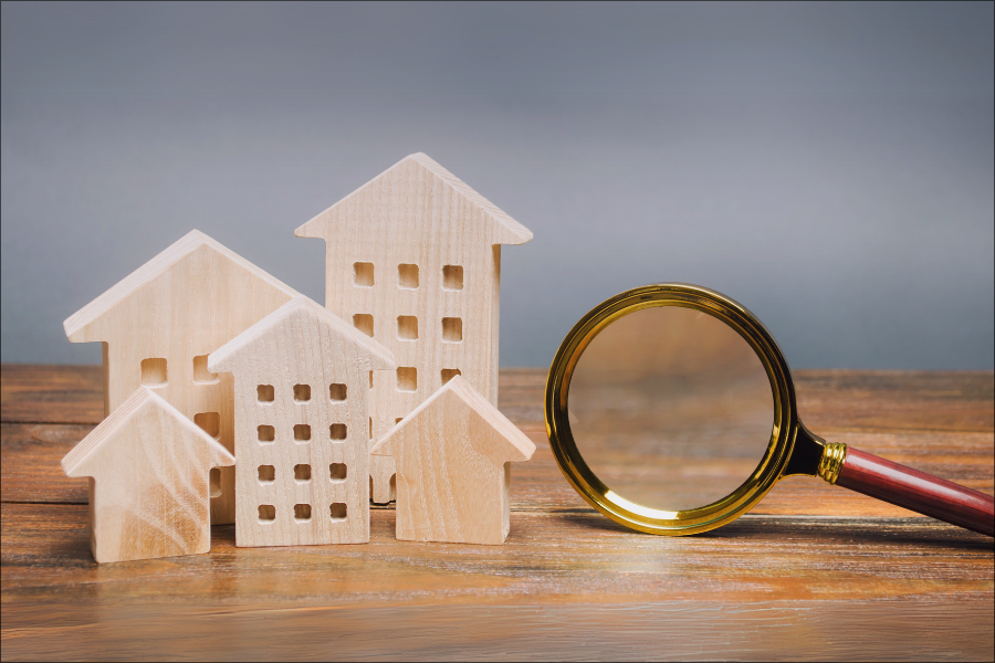 Wooden house models and magnifying glass on wooden surface, symbolising property search and inspection for vacation rental management