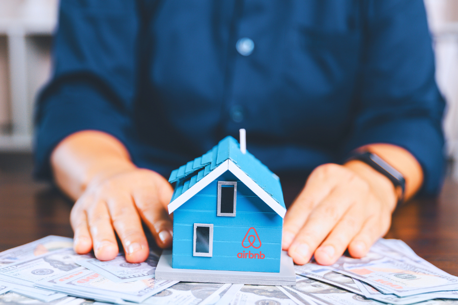 Property manager holding miniature blue house model over property floor plans