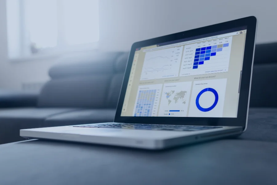 Laptop displaying property management dashboard with occupancy charts, revenue analytics, world map data and performance metrics in blue