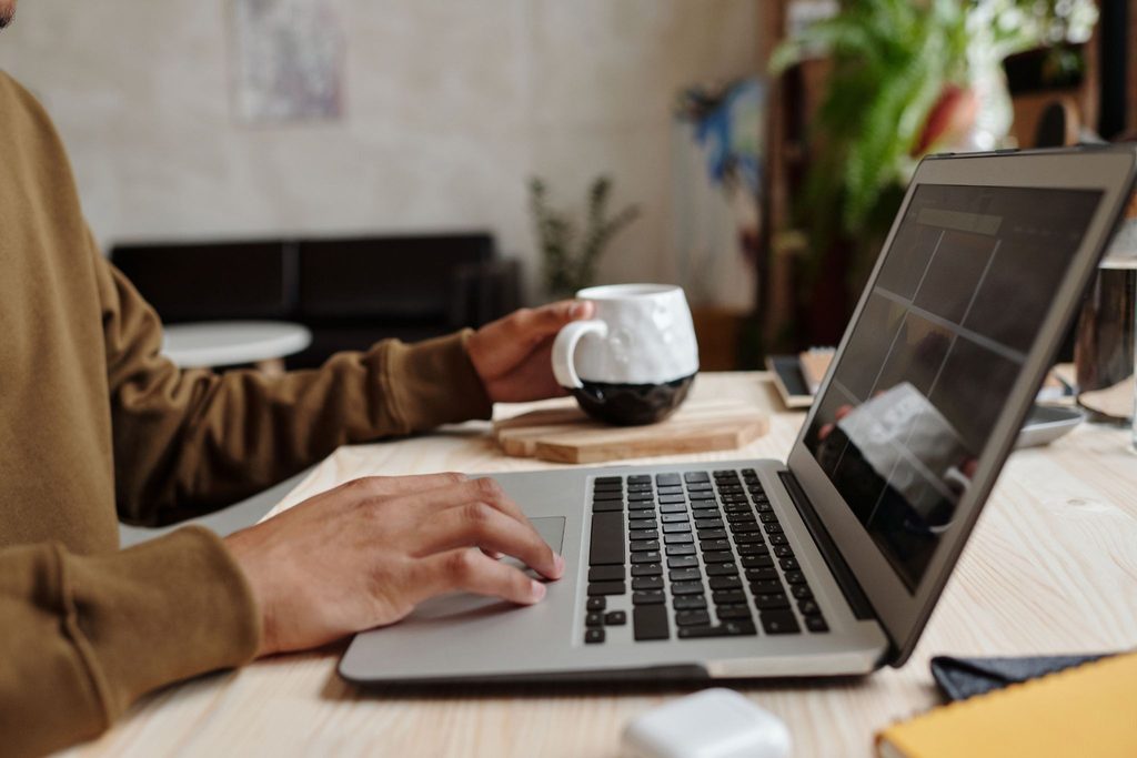 Property manager working at laptop with cup of coffee and tablet at wooden desk in modern office