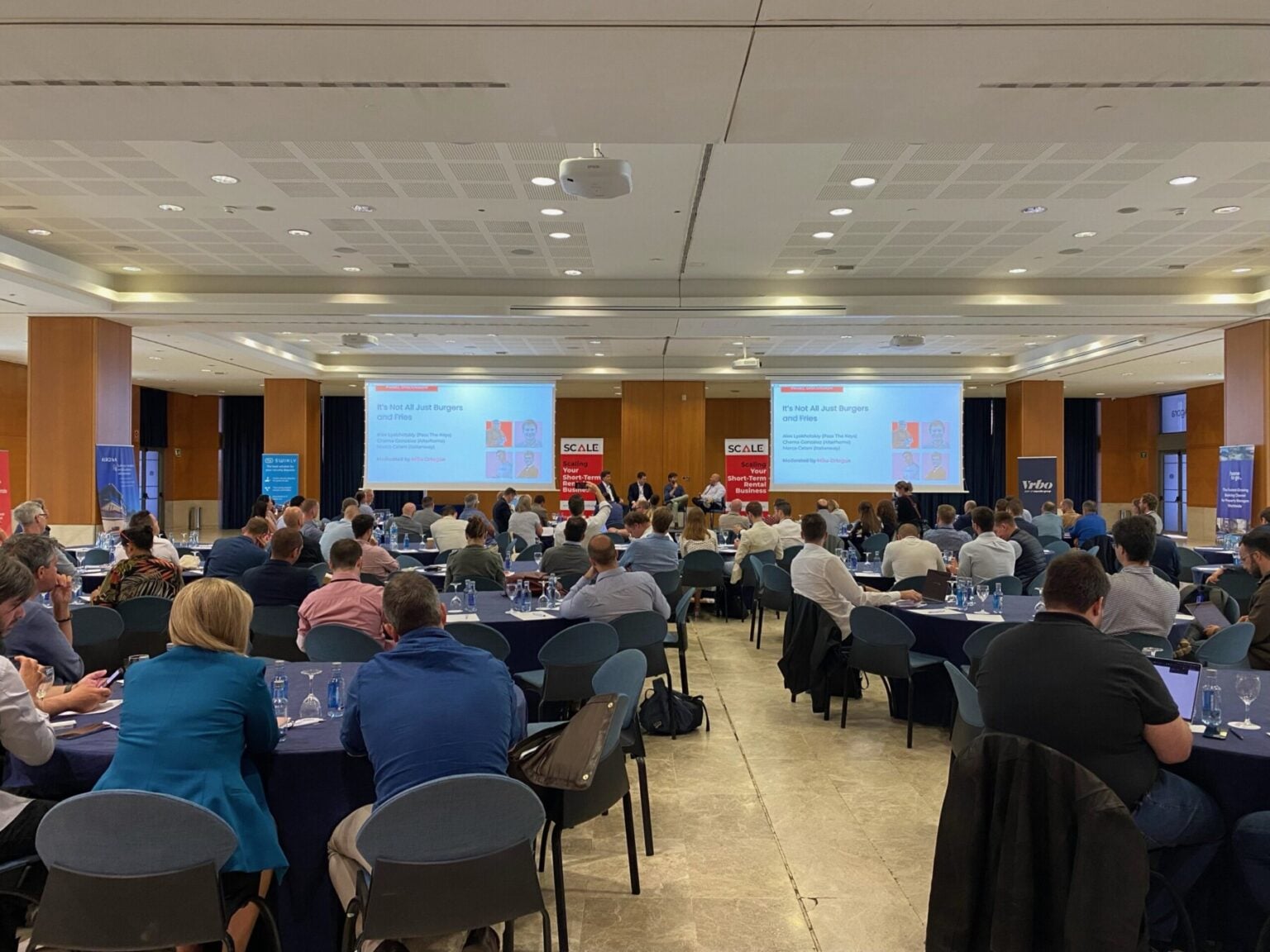 Conference attendees at SCALE Fest 2026 seated at tables facing presentation screens in a large auditorium
