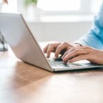 Pessoa a trabalhar num ambiente organizado com gráficos e mapa no ecrã, avaliando software de gestão imobiliária.