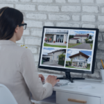 Image of a person at a desk viewing a monitor displaying four different house photos. The setup includes a cup with pencils, decorative items, and a white brick wall background. The screen shows varied residential listings, representing the efficient handling of multiple properties at once. The layout conveys organization, comparison, and streamlined real estate listing management.
