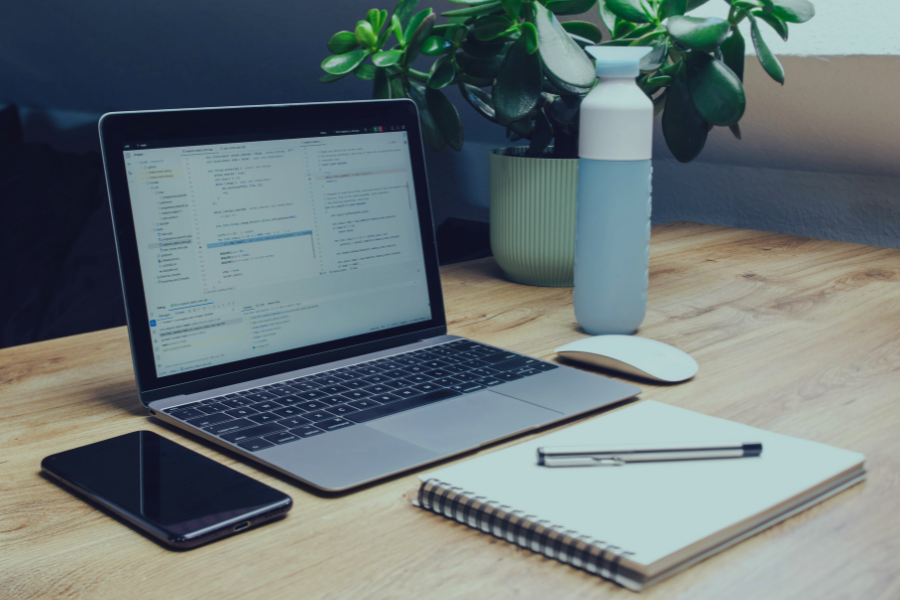 Espaço de trabalho com portátil e caderno a representar Modelos Personalizáveis para Comunicação com Hóspedes para anfitriões e gestores de propriedades