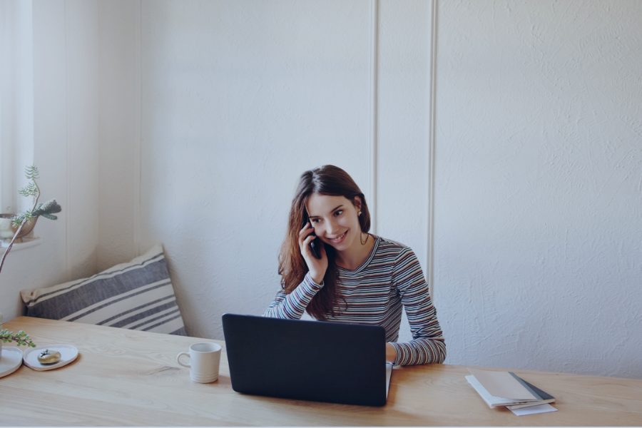 Hôte Airbnb en communication téléphonique devant son ordinateur portable dans un espace de travail minimaliste