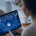 Persona usando portátil con pantalla de seguridad digital mostrando candado cifrado y código binario