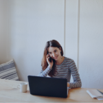 Property manager on video call while reviewing booking management on laptop at desk