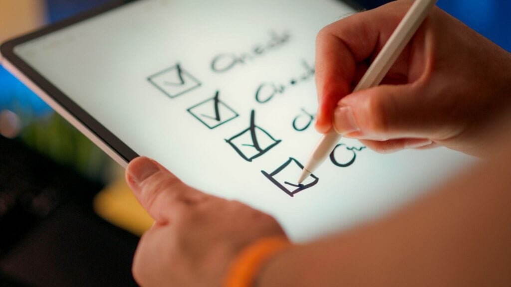 Person using stylus on tablet to check off boxes on a digital checklist