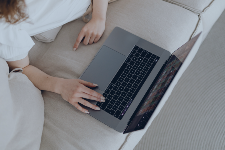 Person using laptop to manage vacation rental bookings on sofa