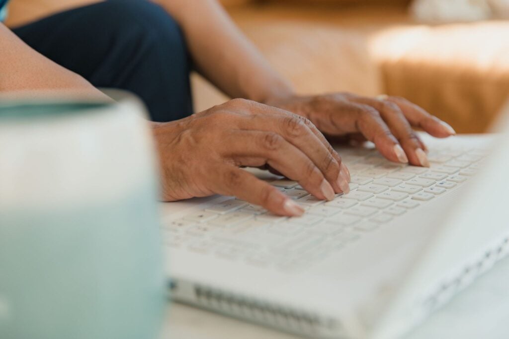 Person typing on laptop keyboard while working at desk