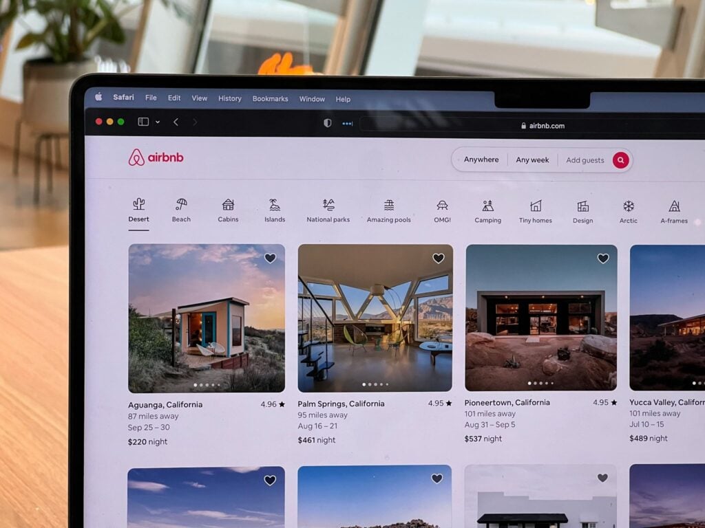 Airbnb website displaying vacation rental listings including desert cabins, beachfront homes, and unique stays in California locations with nightly rates and availability dates.