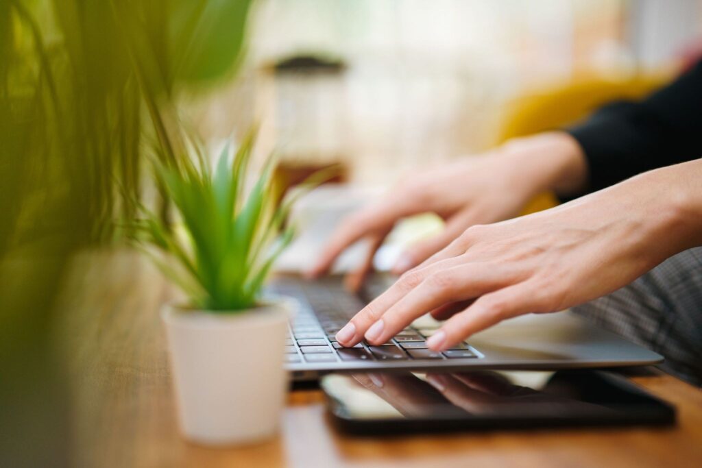 Anfitrión escribiendo en teclado junto a planta de oficina y dispositivos