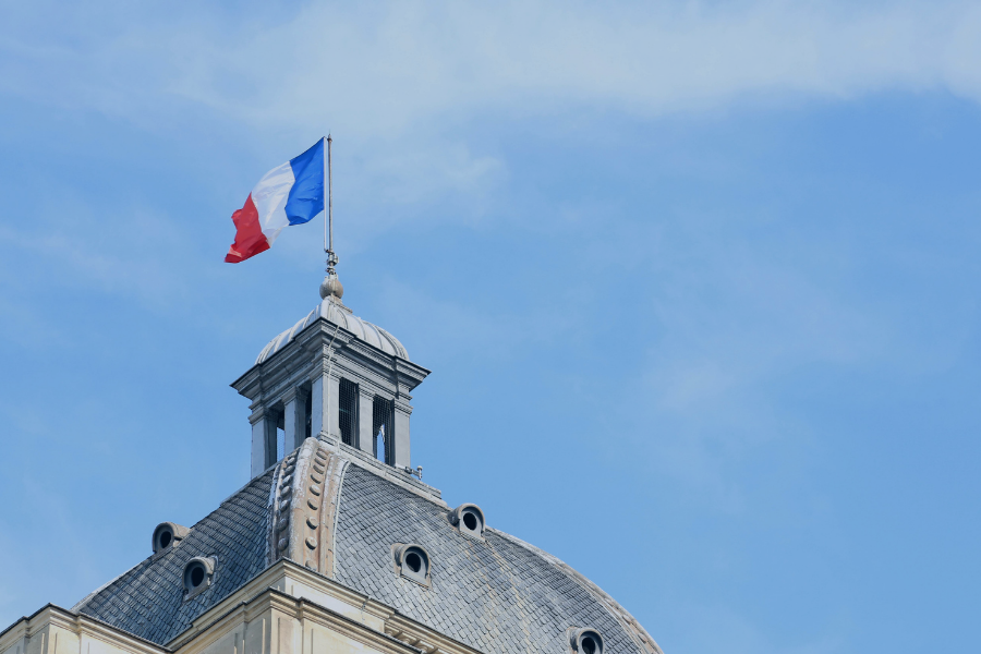 Drapeau français flottant sur le dôme d'un bâtiment administratif sous ciel bleu