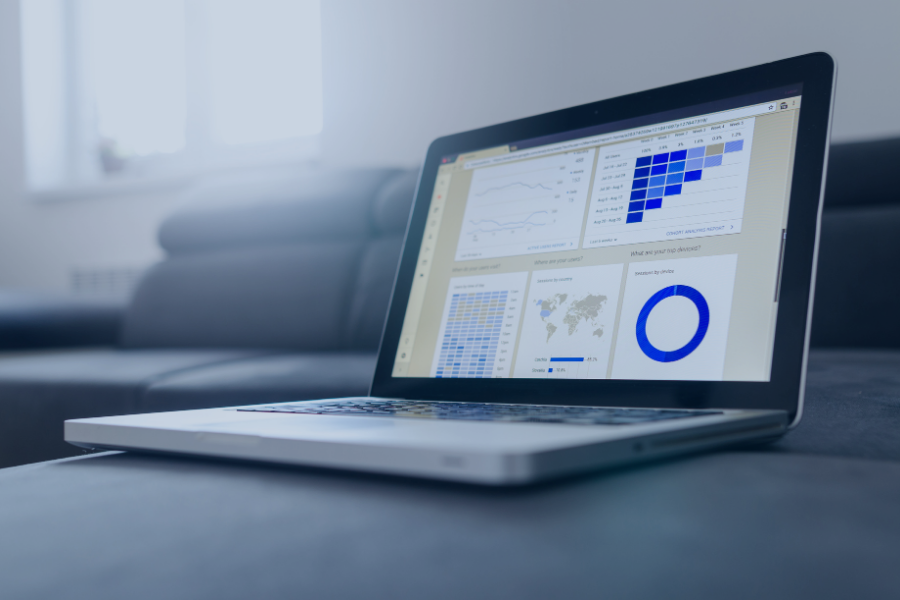 Laptop displaying property management dashboard with occupancy charts, revenue analytics, world map data and performance metrics in blue