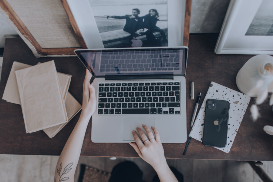 Property manager working at laptop surrounded by booking management tools, guest communication devices and framed holiday rental photographs