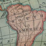 Antique map of South America with regions shaded in pink and green gridlines showing latitude and longitude markers.