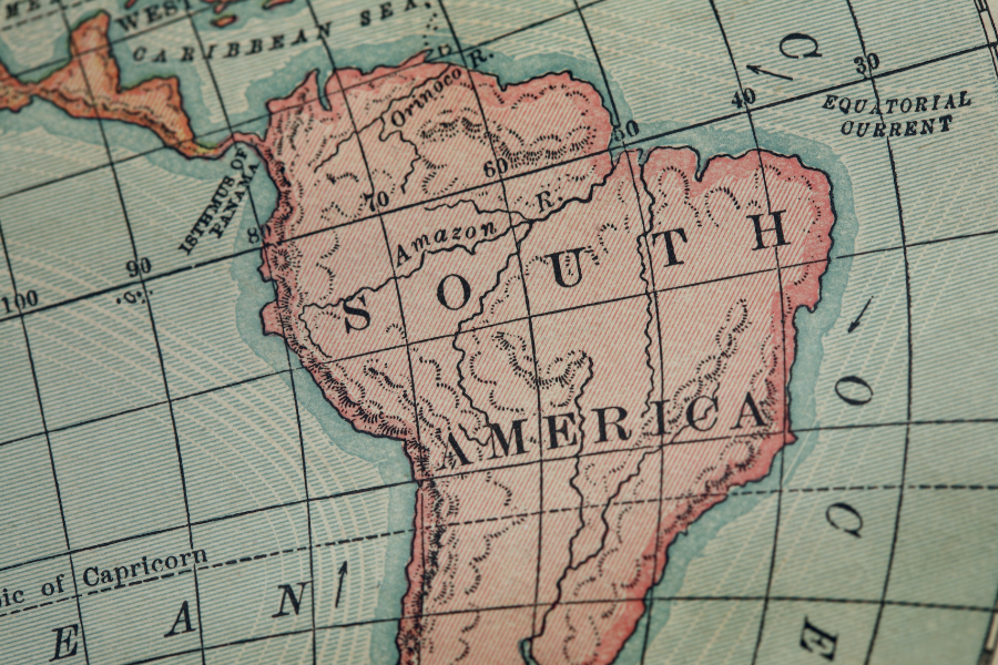 Antique map of South America with regions shaded in pink and green gridlines showing latitude and longitude markers.