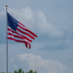 American flag flying on flagpole against cloudy sky