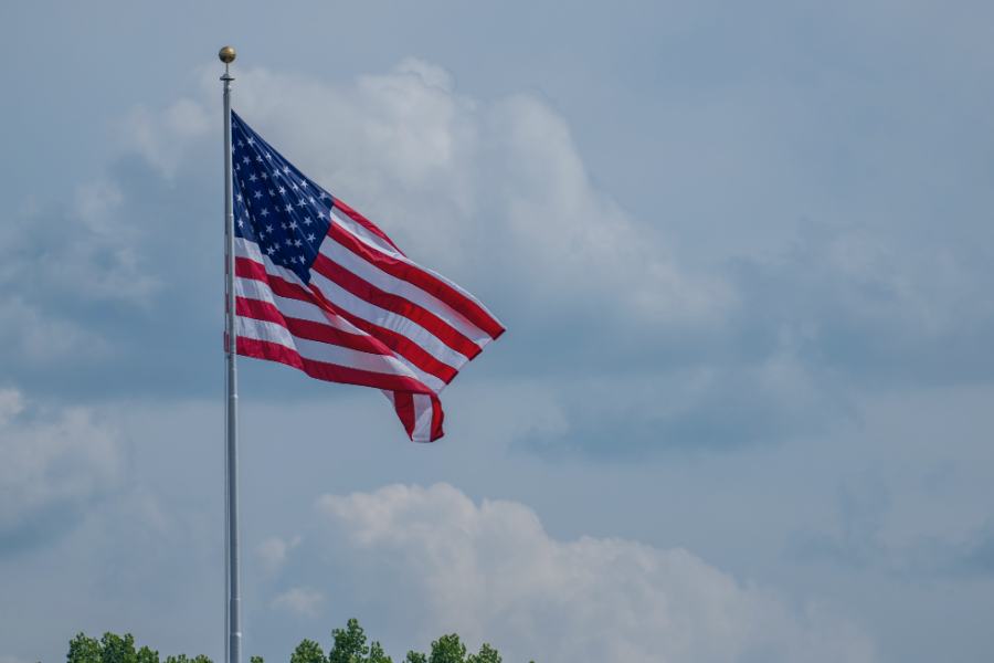 American flag flying on flagpole against cloudy sky