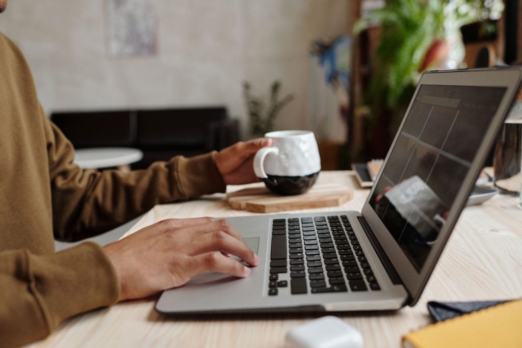 Property manager working at laptop with cup of coffee and tablet at wooden desk in modern office