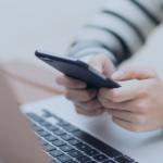 Host using smartphone whilst working at laptop to manage guest communications