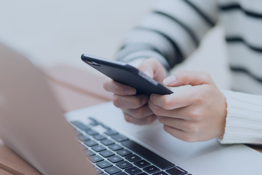 Host using smartphone whilst working at laptop to manage guest communications