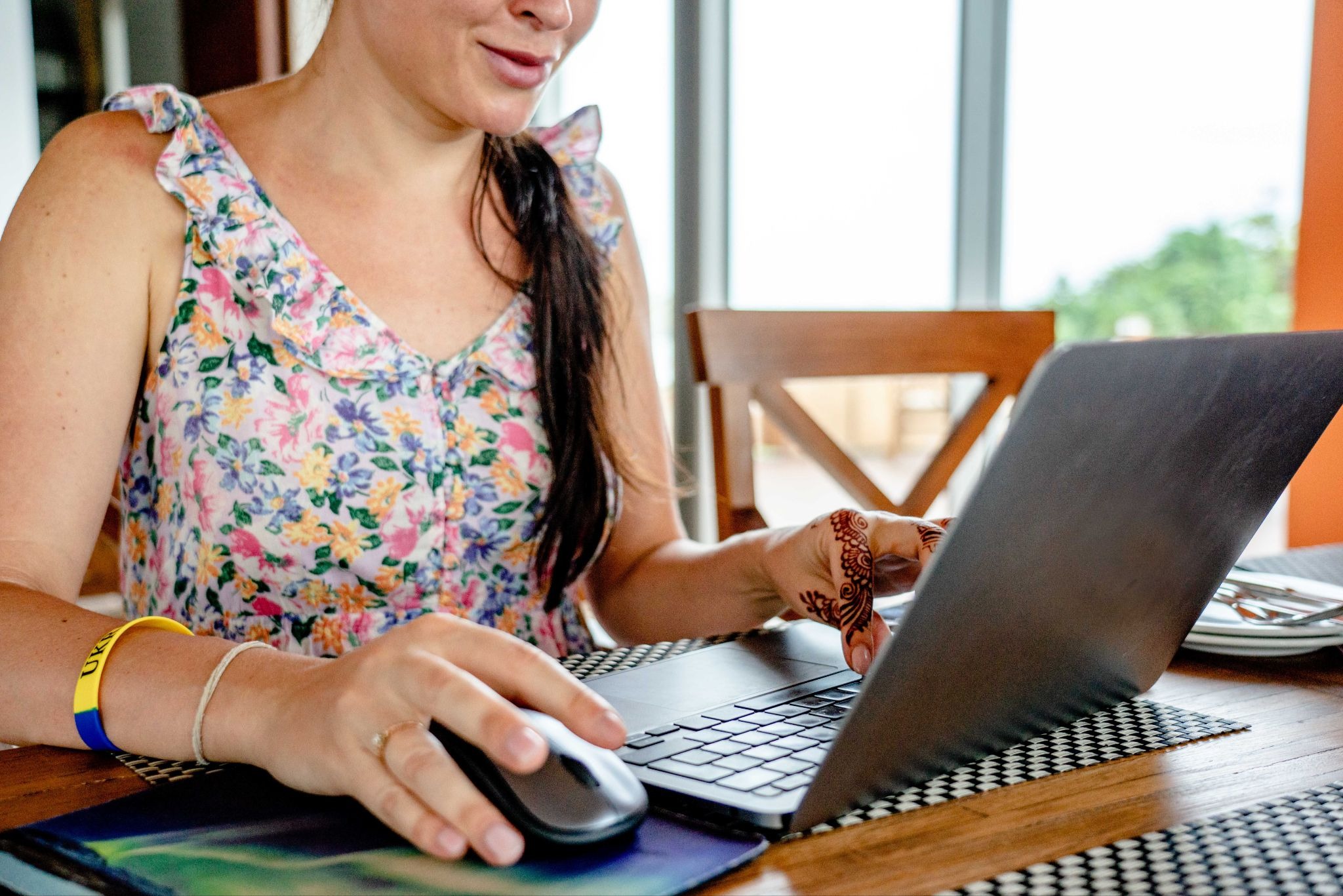 Woman using laptop and mouse at wooden desk while managing vacation rental bookings